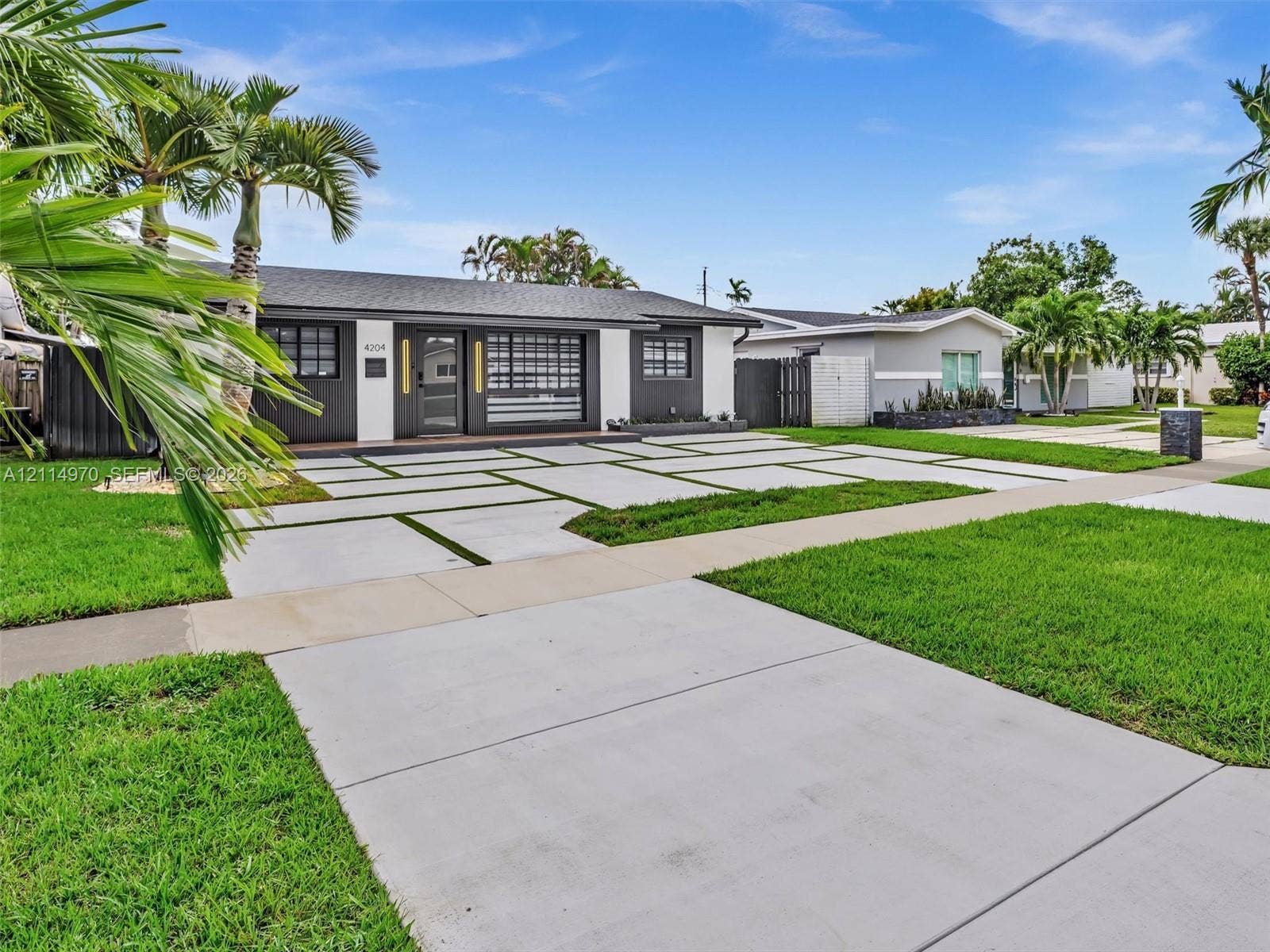 4204 Van Buren Street, Hollywood, Hollywood, FL 33021 Exterior featuring a contemporary concrete paver driveway with integrated turf, dark-toned siding with contrasting white trim, and a multi-lite front door