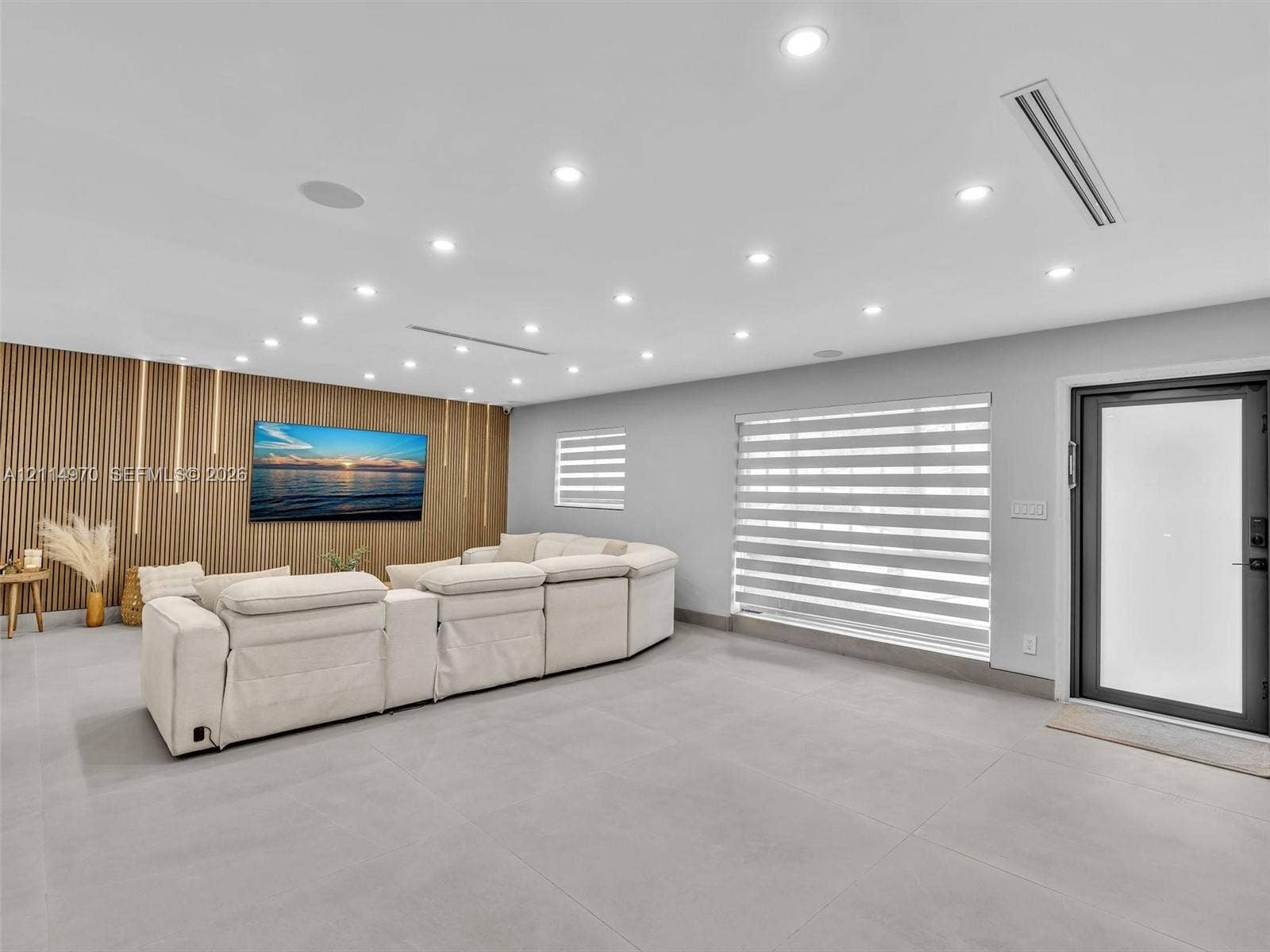 4204 Van Buren Street, Hollywood, Hollywood, FL 33021 Vertical wood-slat accent wall, neutral large-format tile flooring, recessed ceiling lighting, horizontal banded window shades, and exterior-grade door with frosted glass panel