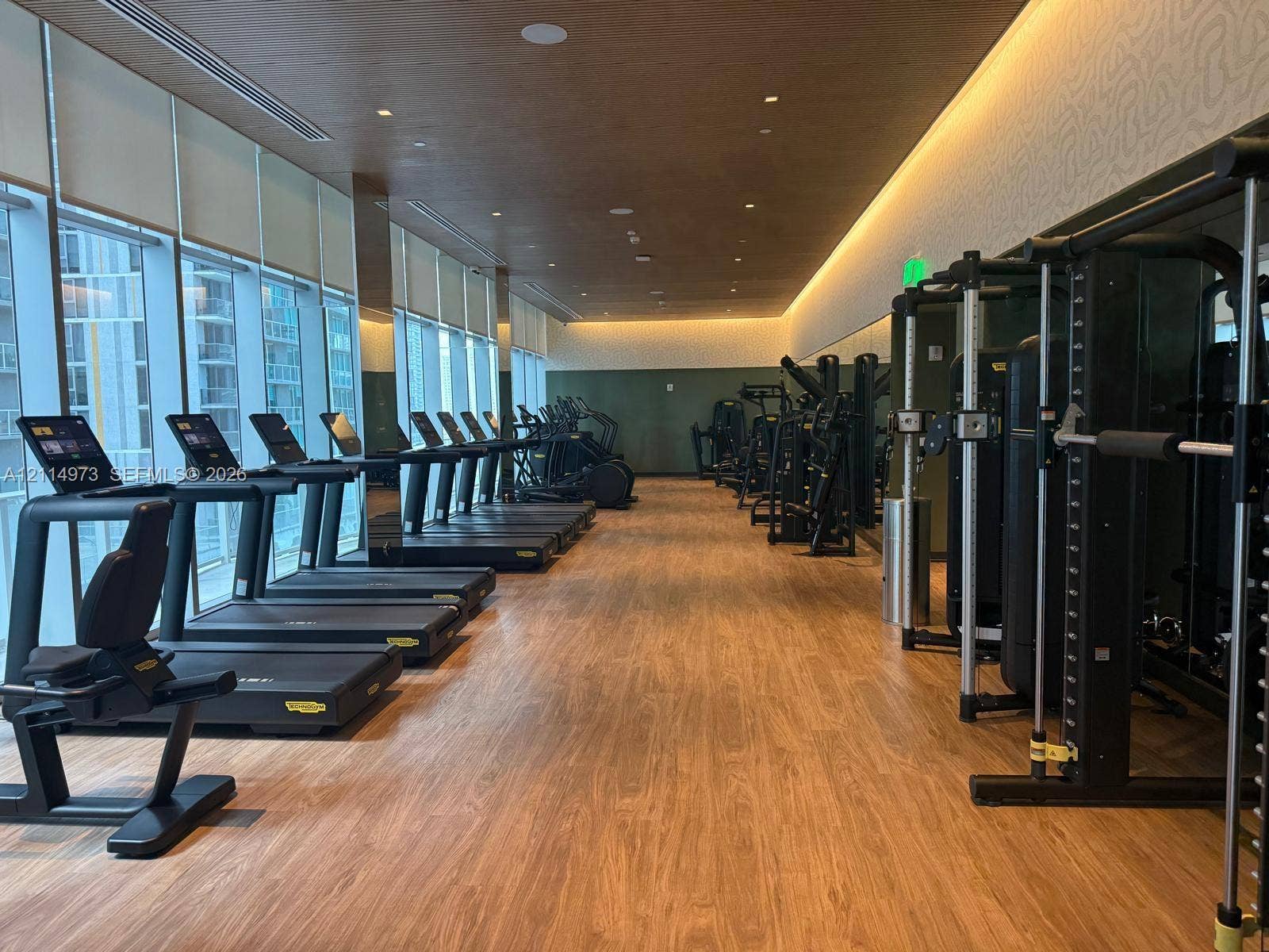 77 SE 5th Street, #2406, Miami, FL 33131 Fitness center featuring wood-finish flooring, floor-to-ceiling windows, recessed cove lighting, and wood-paneled ceiling detail
