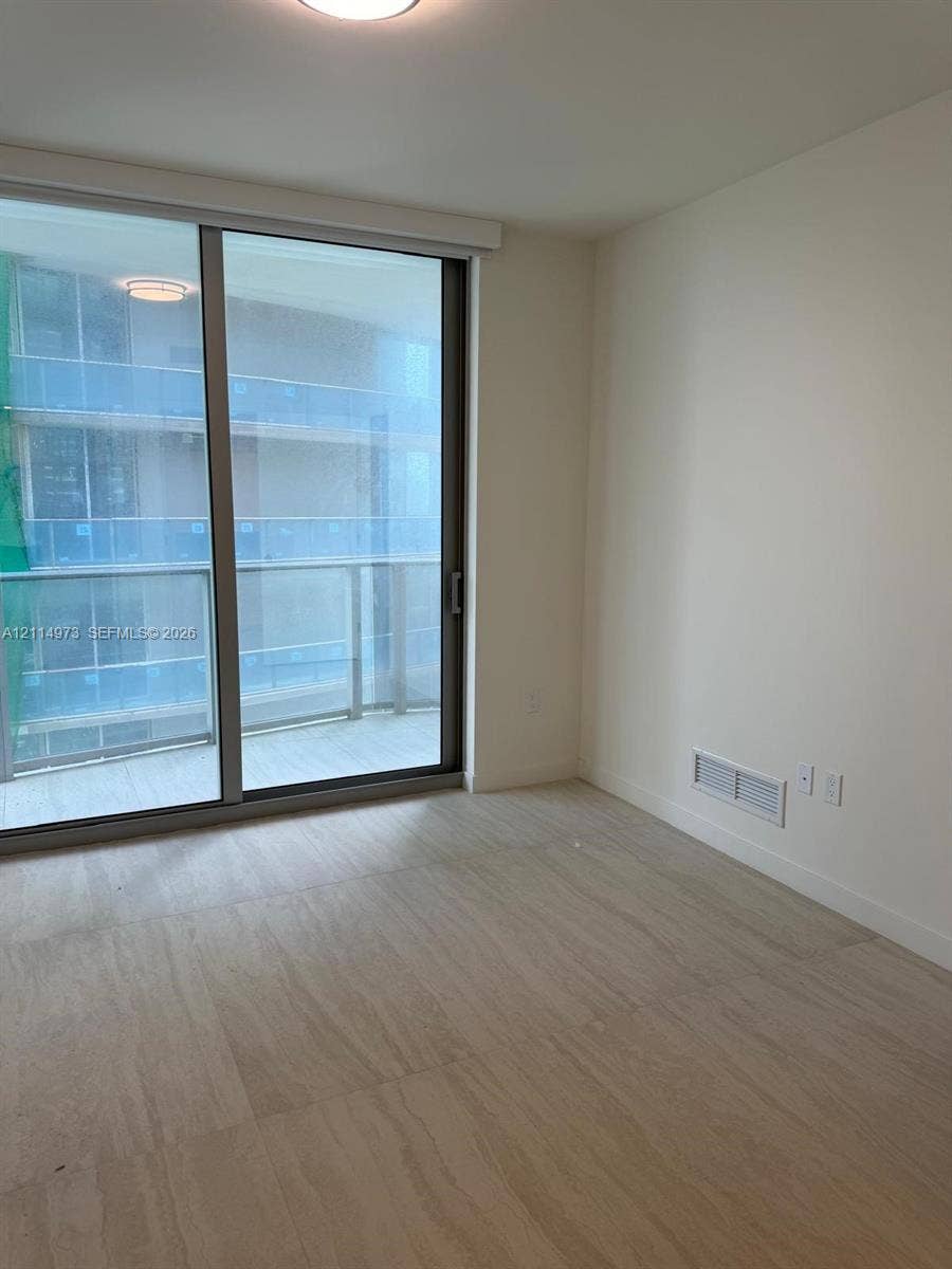 77 SE 5th Street, #2406, Miami, FL 33131 Floor-to-ceiling sliding glass door, private balcony with glass railing, and wood-finish flooring