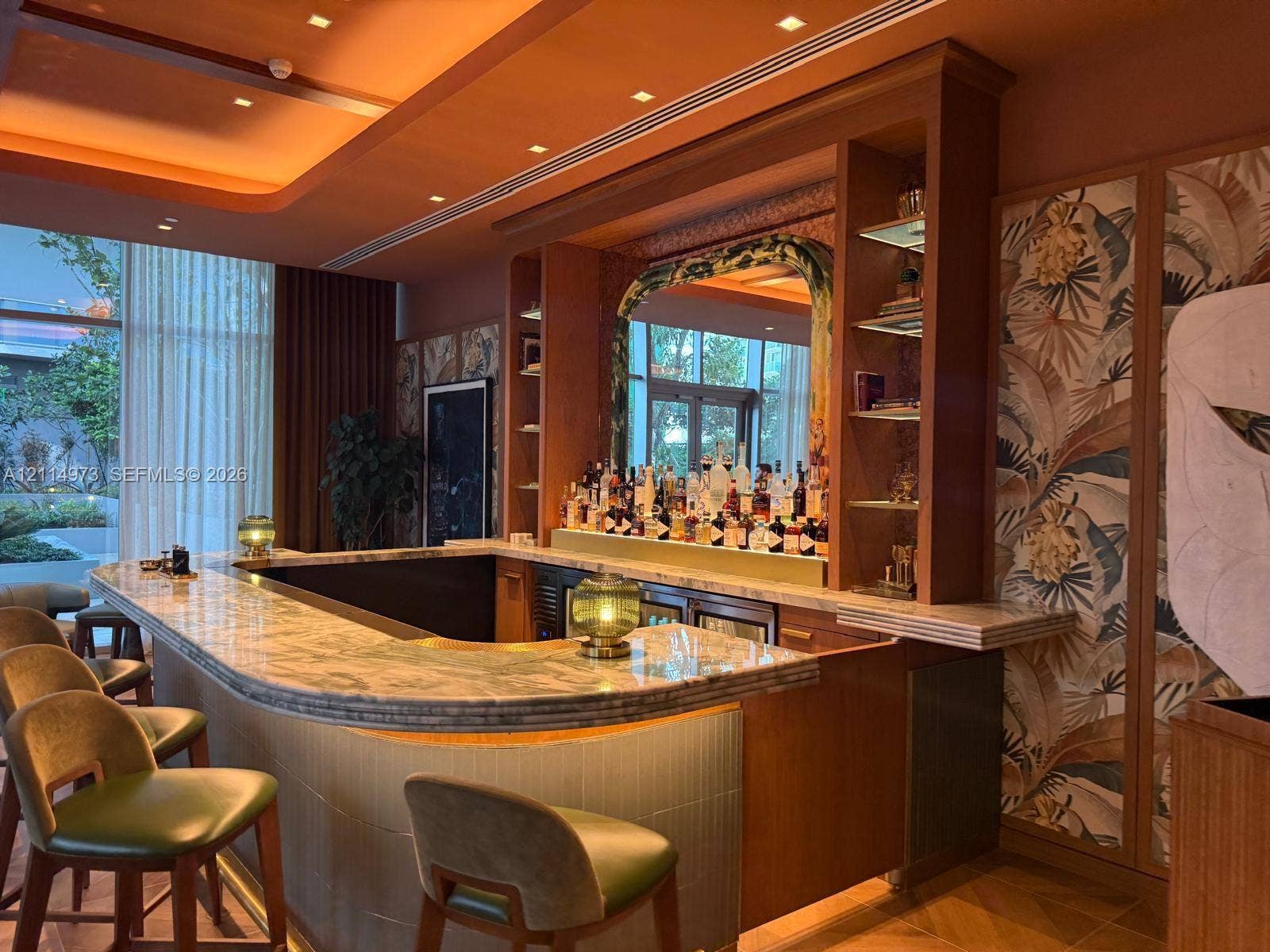 77 SE 5th Street, #2406, Miami, FL 33131 Custom bar featuring a stone countertop, built-in wooden cabinetry, recessed tray ceiling lighting, and decorative wall paneling