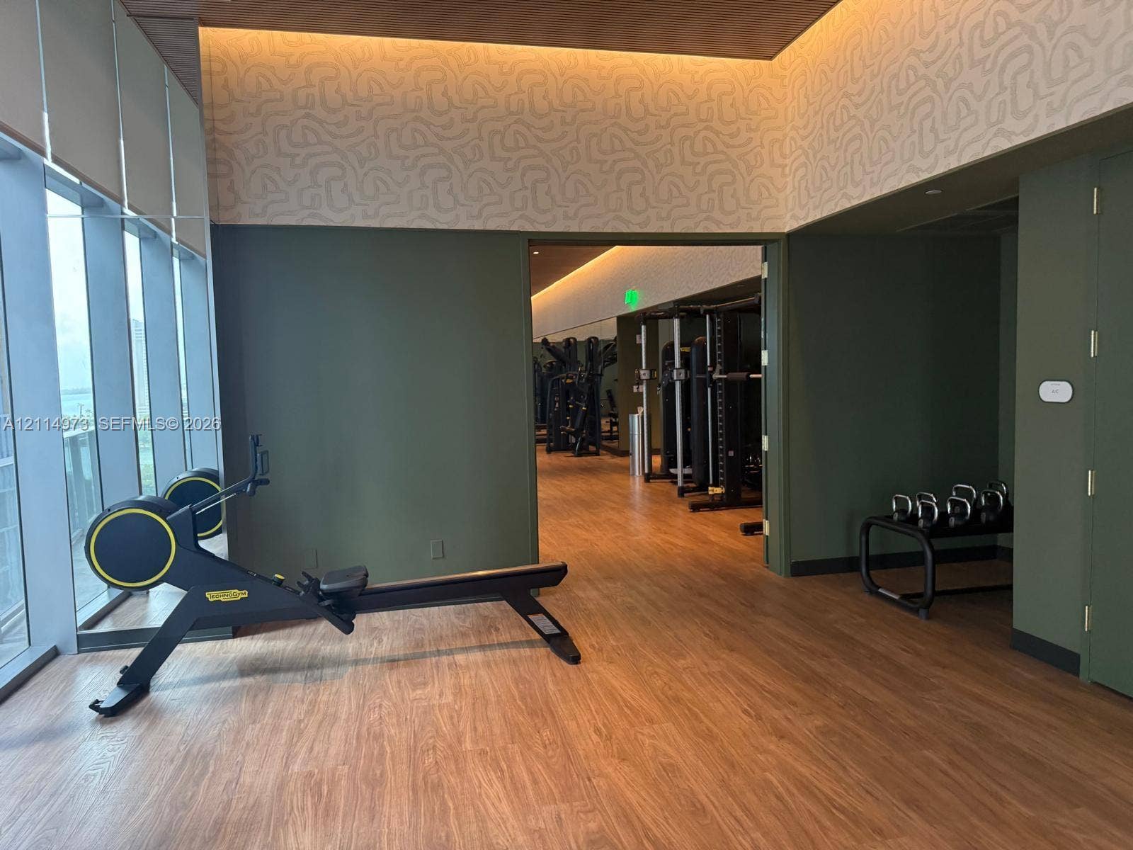 77 SE 5th Street, #2406, Miami, FL 33131 Fitness center featuring floor-to-ceiling windows, wood-finish flooring, recessed cove lighting, and textured wall accents