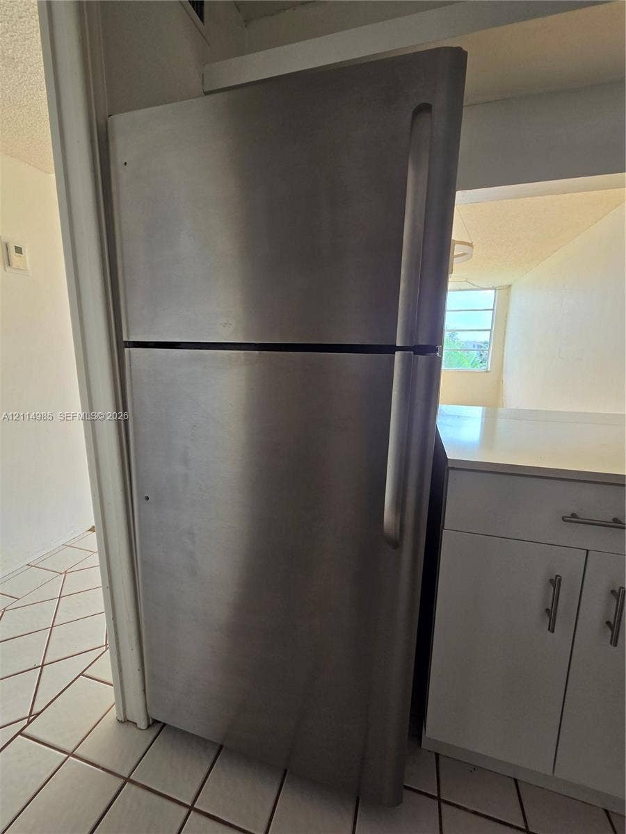 9441 Live Oak Place, #308, Davie, Davie, FL 33324 Stainless steel top-freezer refrigerator, white cabinetry with silver-tone hardware, and white ceramic floor tile