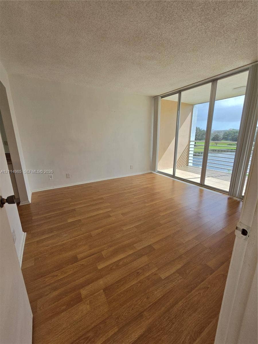 9441 Live Oak Place, #308, Davie, Davie, FL 33324 Wood-finish flooring, full-height sliding glass doors, and an outdoor balcony with metal railing