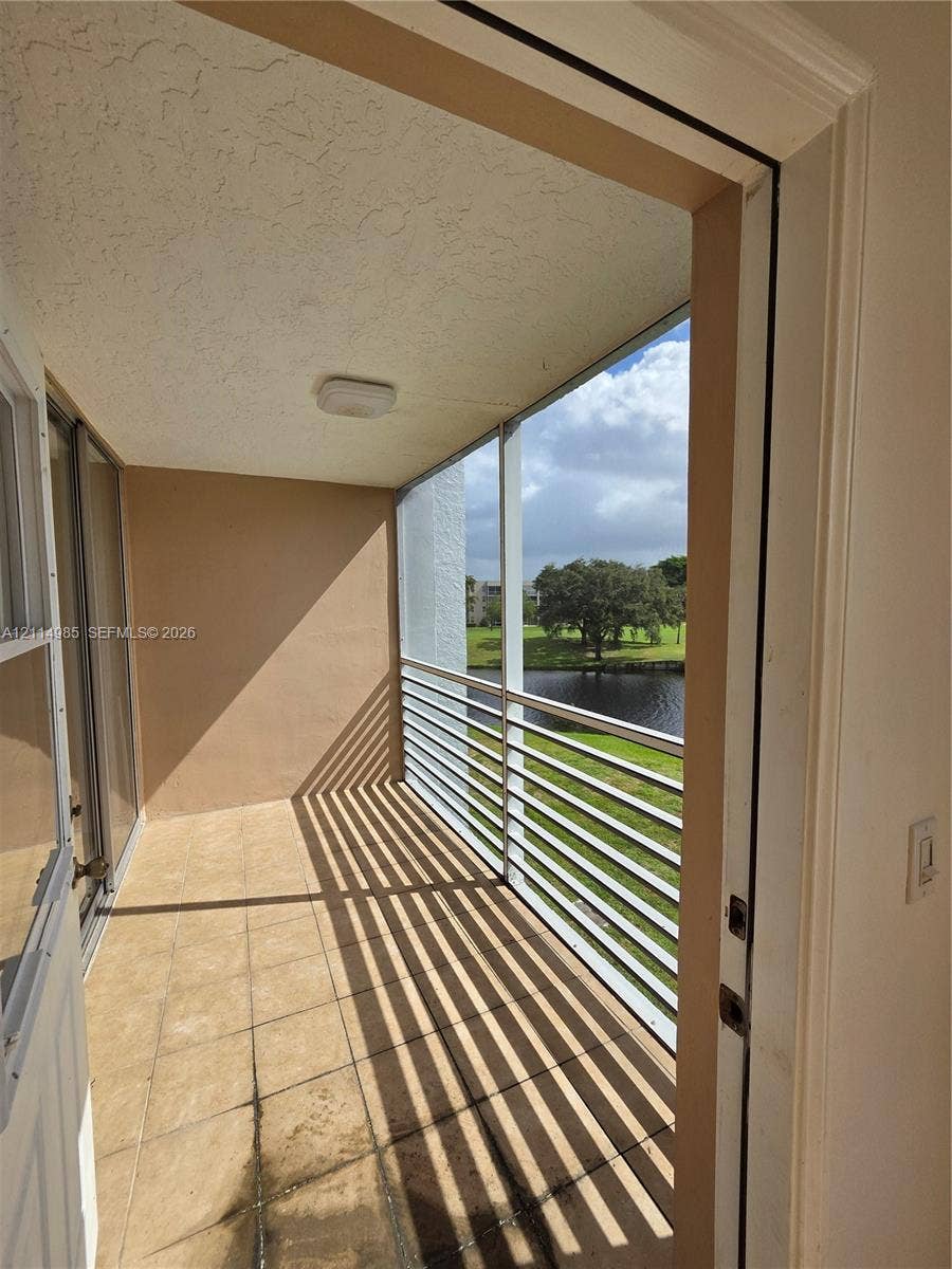 9441 Live Oak Place, #308, Davie, Davie, FL 33324 Covered balcony featuring tile flooring, a screened enclosure, and aluminum railings with water scenery