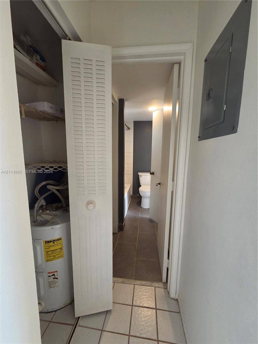 9441 Live Oak Place, #308, Davie, Davie, FL 33324 Utility closet featuring louvered bi-fold doors, white ceramic tile flooring, and integrated water heater