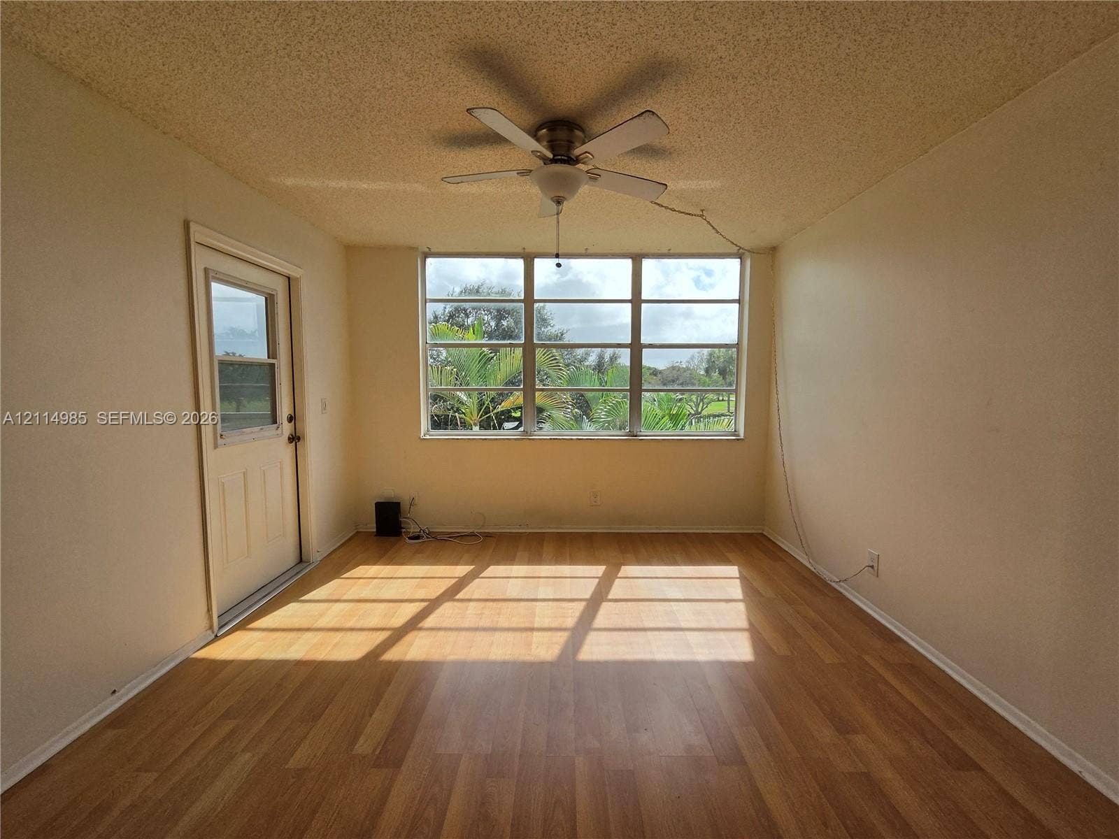9441 Live Oak Place, #308, Davie, Davie, FL 33324 Room featuring wood-finish flooring, a multi-pane window, a ceiling fan with integrated lighting, and an exterior door