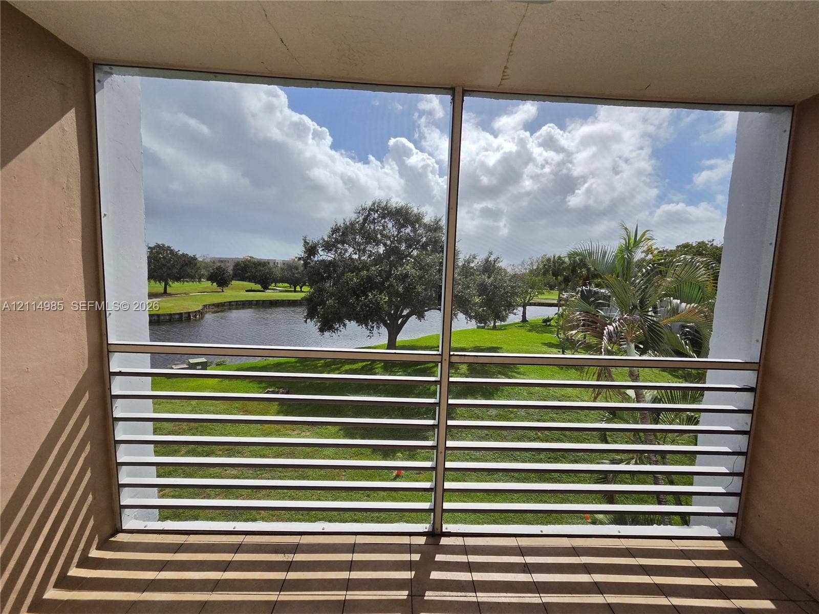 9441 Live Oak Place, #308, Davie, Davie, FL 33324 Screened-in balcony featuring tile flooring and horizontal metal railings overlooking a water feature and manicured grounds