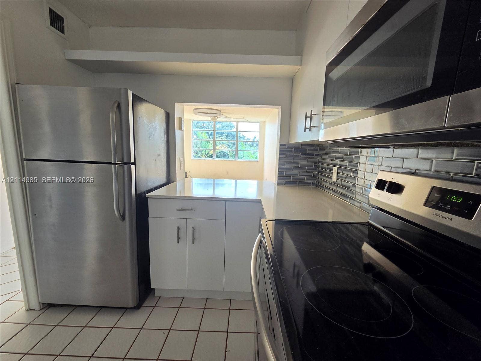 9441 Live Oak Place, #308, Davie, Davie, FL 33324 Kitchen featuring white cabinetry, solid-surface countertops, stainless steel appliances, and a tiled backsplash