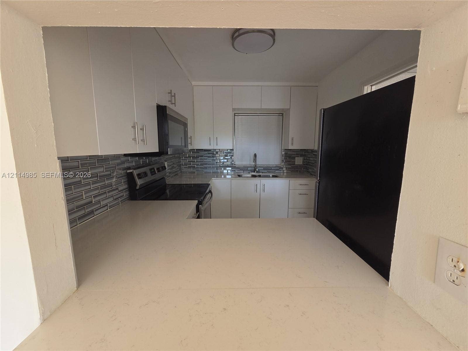 9441 Live Oak Place, #308, Davie, Davie, FL 33324 Kitchen featuring white cabinetry, solid-surface countertops, horizontal tile backsplash, stainless steel appliances, and a pass-through counter