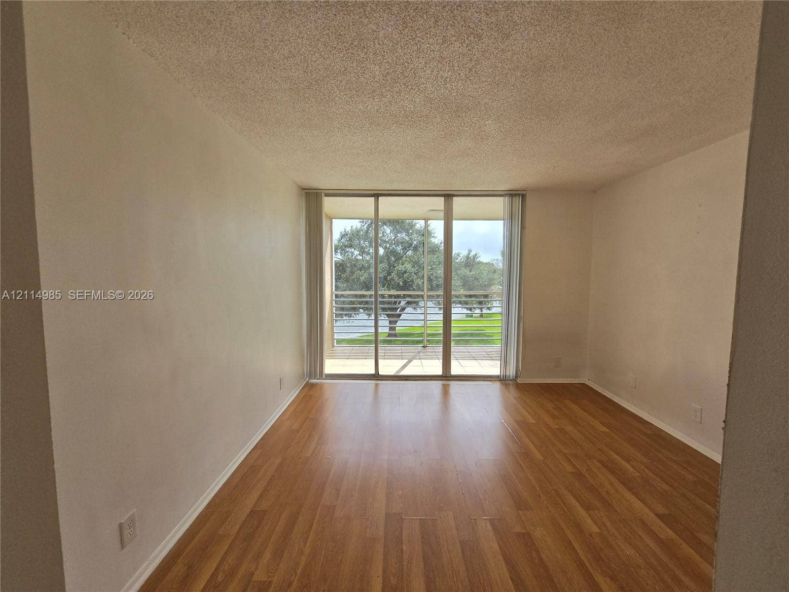 9441 Live Oak Place, #308, Davie, Davie, FL 33324 Interior space featuring wood-finish flooring, textured ceiling, and floor-to-ceiling sliding glass doors opening to an exterior balcony