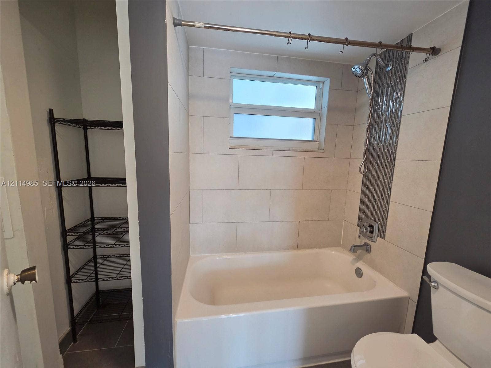 9441 Live Oak Place, #308, Davie, Davie, FL 33324 Bathtub with large-format ceramic tile surround, vertical decorative mosaic tile accent, and built-in storage alcove