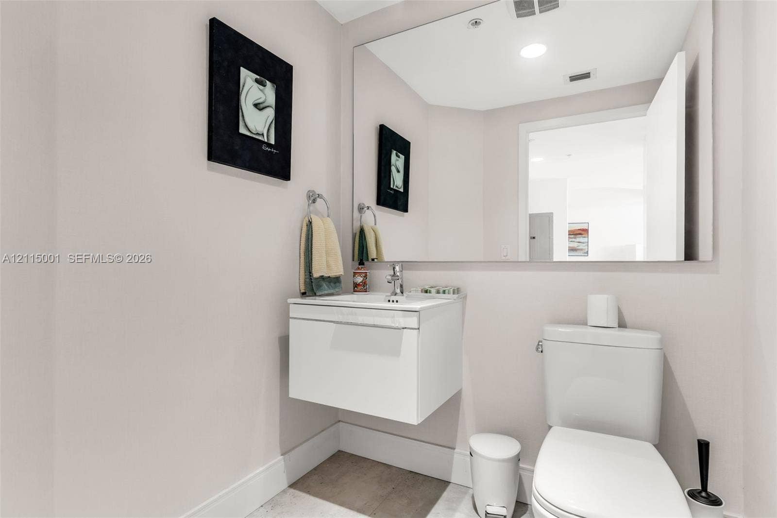 Modern floating vanity featuring a white finish, integrated sink, chrome faucet, and expansive wall-mounted mirror