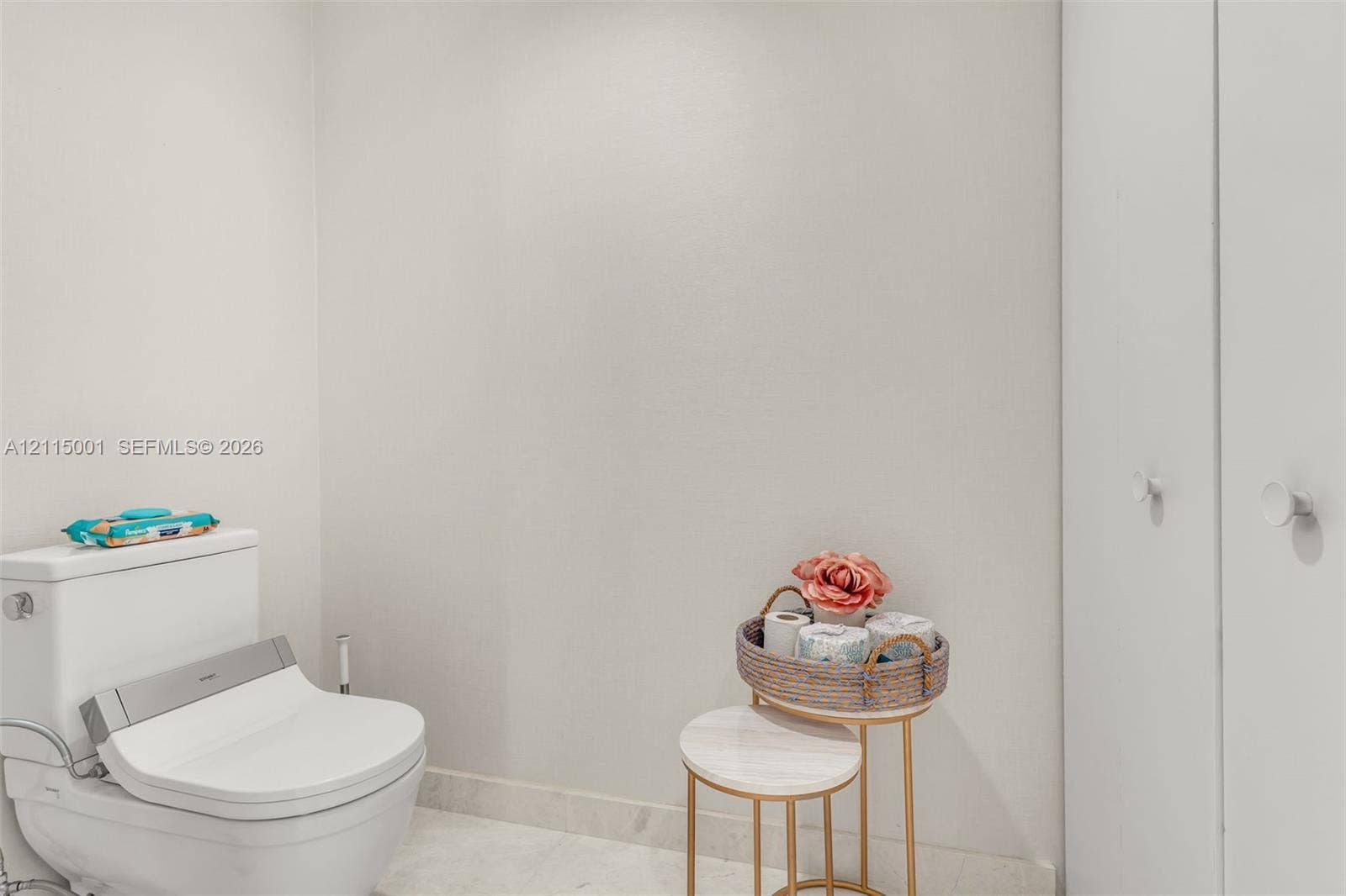 White dual-flush toilet with integrated bidet seat and double-door cabinetry featuring round knob hardware