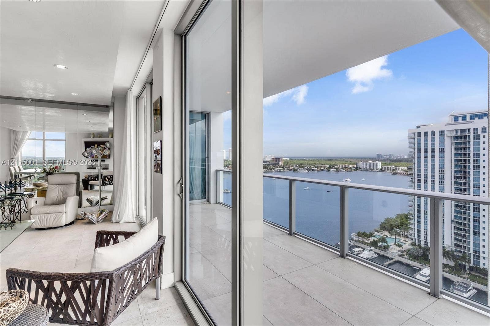 Covered balcony featuring oversized neutral tile flooring, glass panel railings, and full-height sliding glass doors