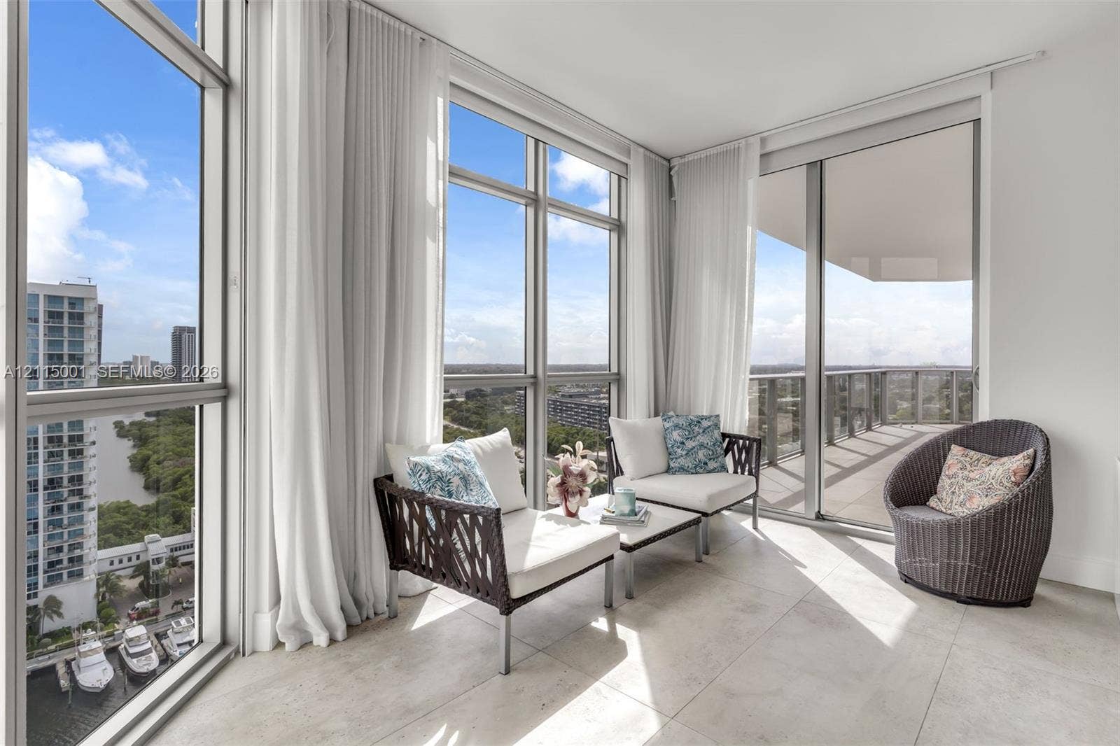 Floor-to-ceiling windows, large-format tile flooring, metal-framed glass sliding doors, and a wrap-around balcony