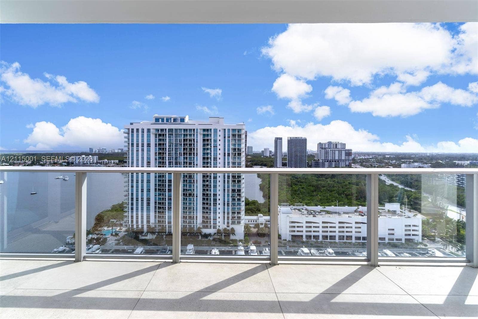 Covered balcony featuring expansive tile flooring and a transparent glass railing