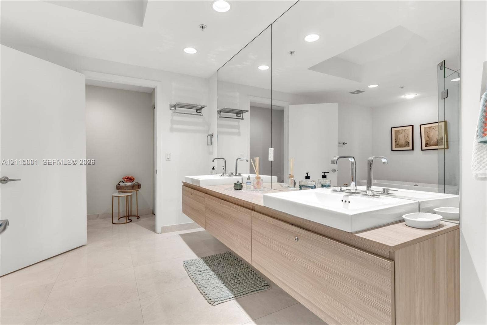 Floating wood-finish double vanity featuring integrated rectangular sinks, polished chrome faucets, and an expansive wall-mounted mirror