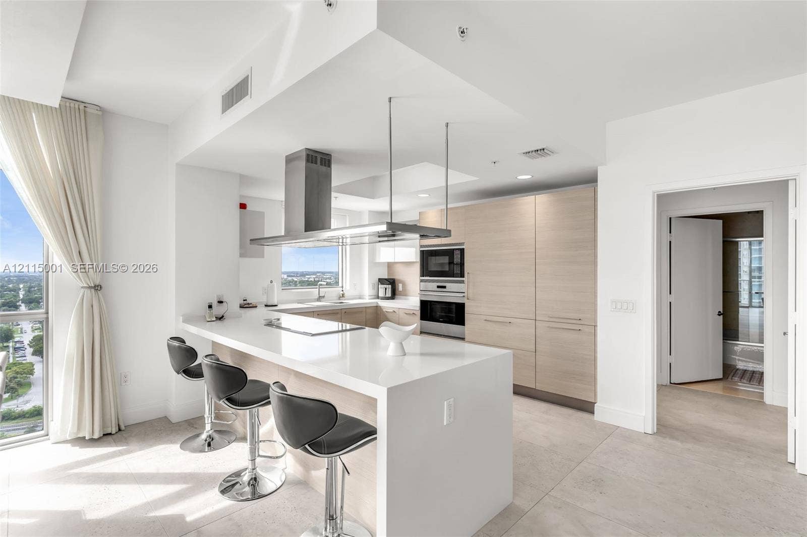 Kitchen featuring quartz countertops, flat-panel wood-finish cabinetry, stainless steel built-in oven and microwave, and a stainless steel suspended range hood