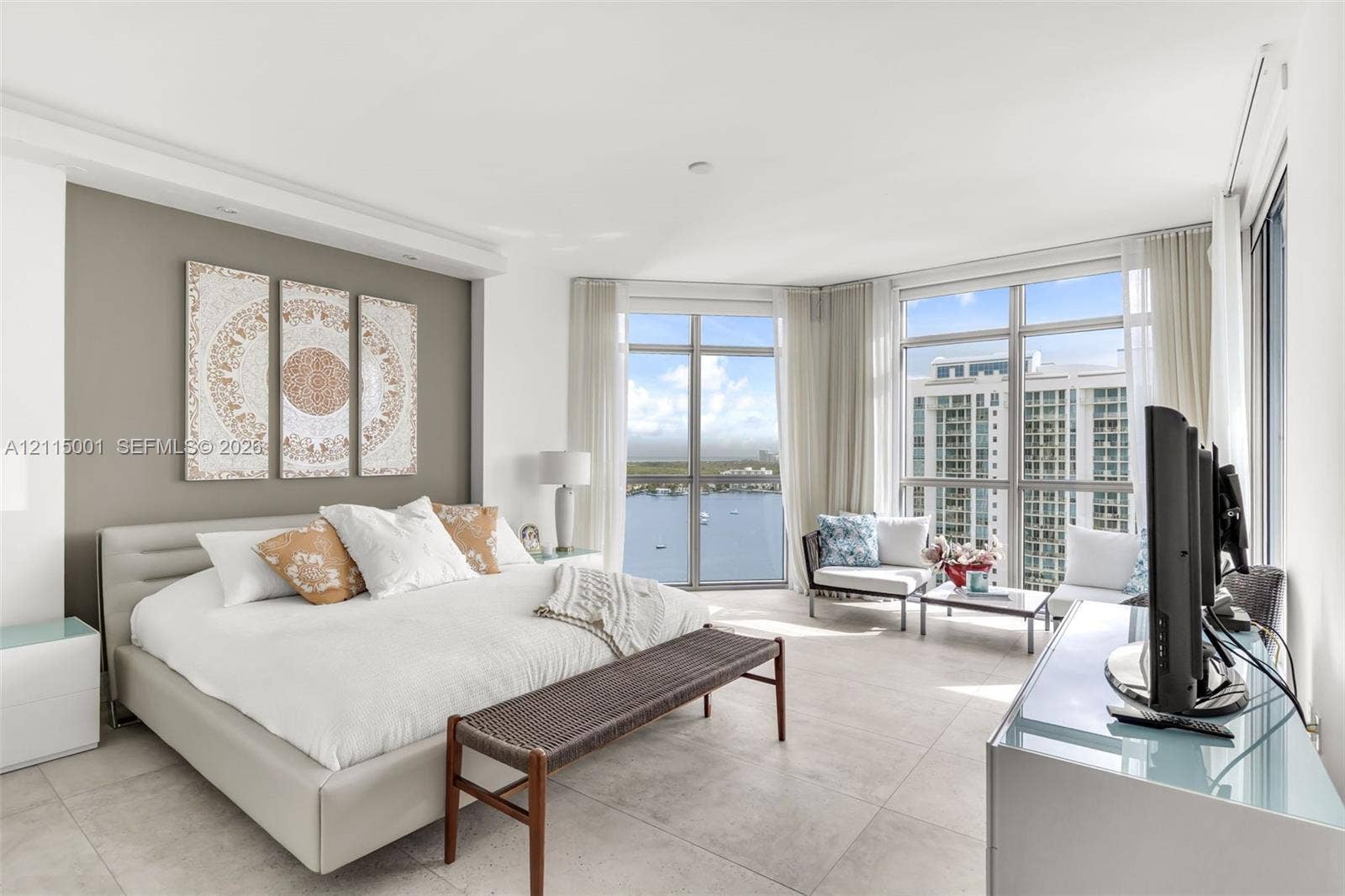 Floor-to-ceiling windows, neutral tile flooring, accent wall, and expansive water backdrop