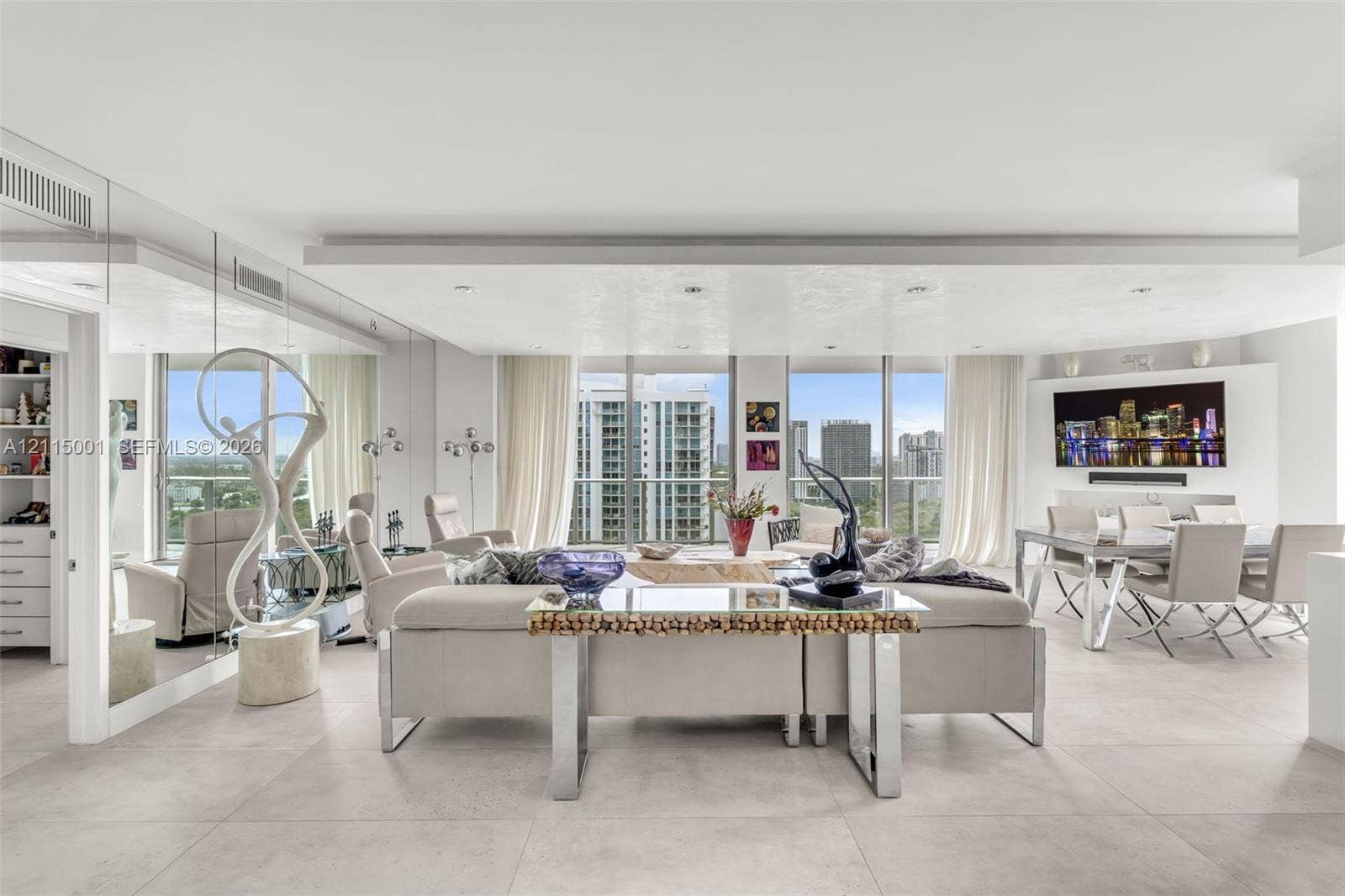 Open-concept living area featuring large-format tile flooring, floor-to-ceiling windows, a mirrored wall, and recessed tray ceiling lighting
