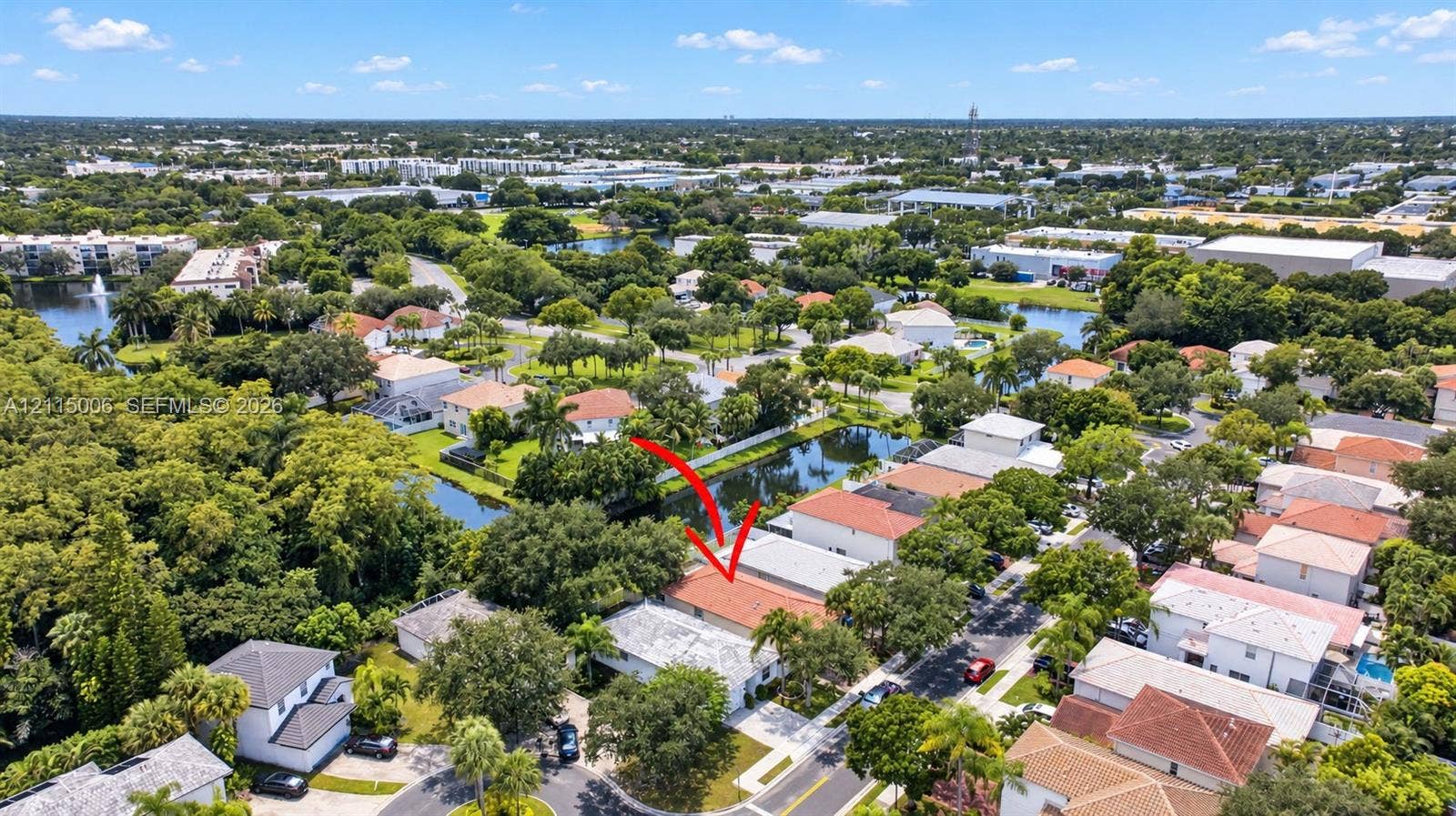 4812 NW 19th Street, Coconut Creek, FL 33063 Aerial perspective featuring a single-story residence with a multi-gabled terracotta-style roof, situated on a lot bordering a water feature, surrounded by mature trees and established landscaping