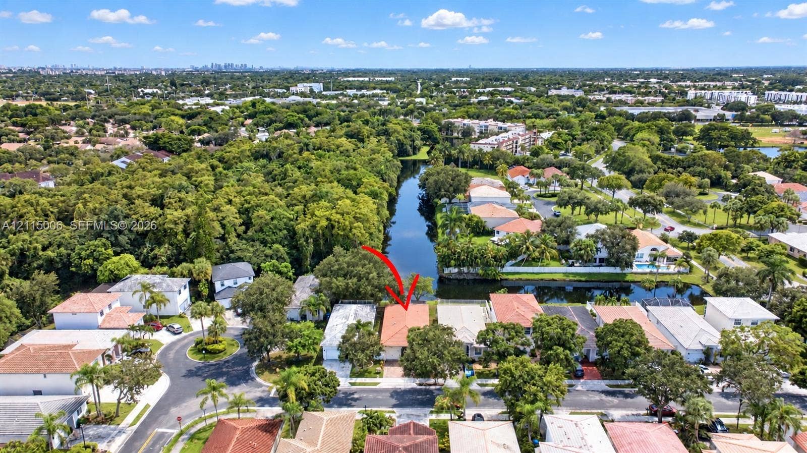 4812 NW 19th Street, Coconut Creek, FL 33063 Aerial perspective of waterfront property featuring a tile roof, paved driveway, and established tree canopy