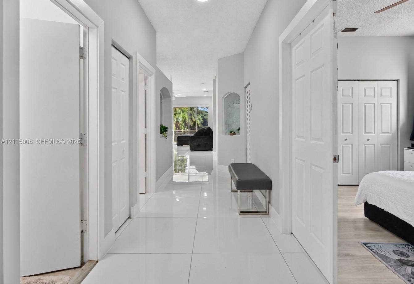 4812 NW 19th Street, Coconut Creek, FL 33063 Hallway featuring glossy tile flooring, neutral wall color, arched wall niches, and paneled interior doors