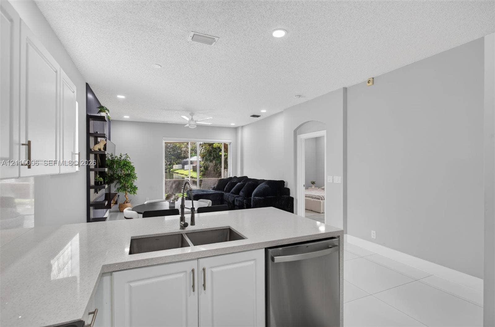4812 NW 19th Street, Coconut Creek, FL 33063 Kitchen featuring white cabinetry, solid-surface countertops, dual-basin stainless steel sink, and stainless steel dishwasher, complemented by tile flooring throughout