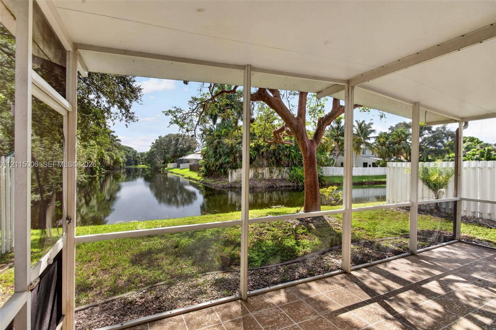 4812 NW 19th Street, Coconut Creek, FL 33063 Screened-in lanai featuring tile flooring, a solid ceiling, and water frontage with mature trees