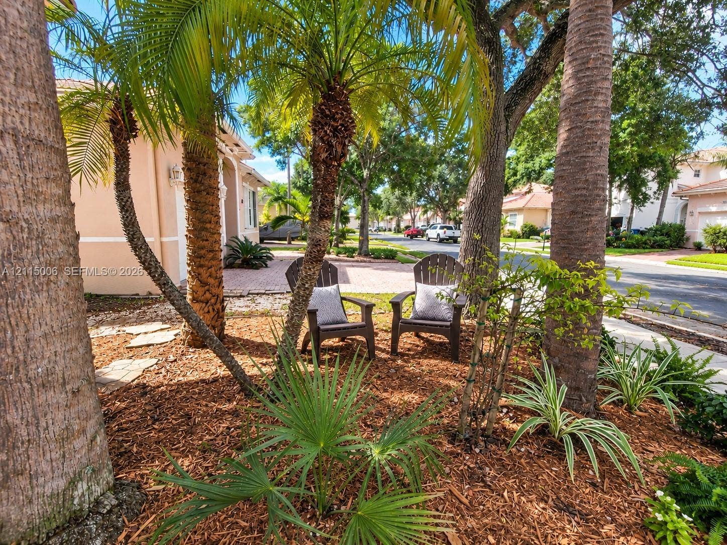 4812 NW 19th Street, Coconut Creek, FL 33063 Landscaped front grounds featuring mature palm trees, diverse ornamental shrubbery, stone-paver hardscaping, and mulch bedding