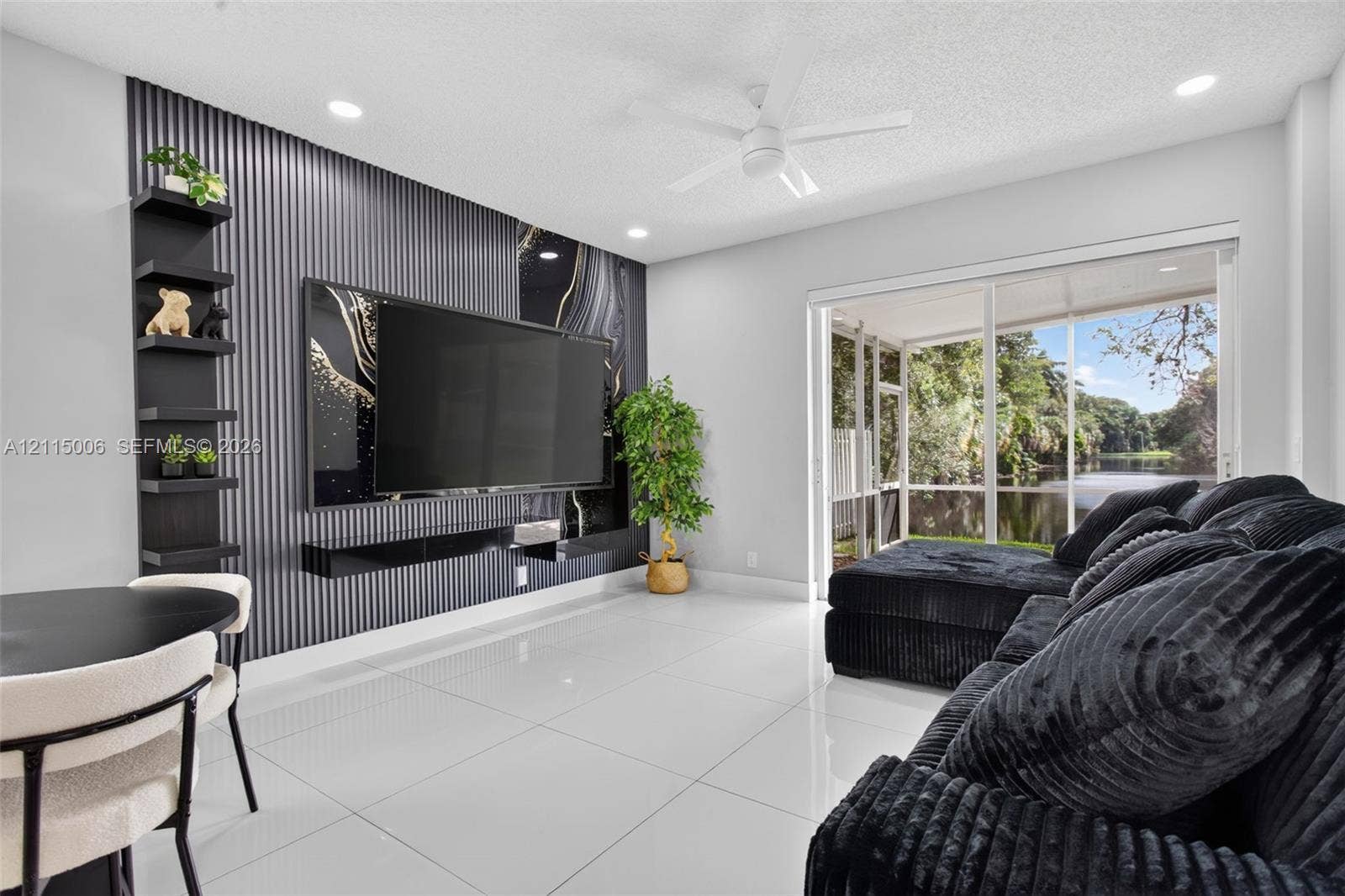 4812 NW 19th Street, Coconut Creek, FL 33063 Accent wall featuring textured vertical paneling and integrated shelving, large-format tile flooring, recessed ceiling lighting, and sliding glass doors opening to a screened enclosure