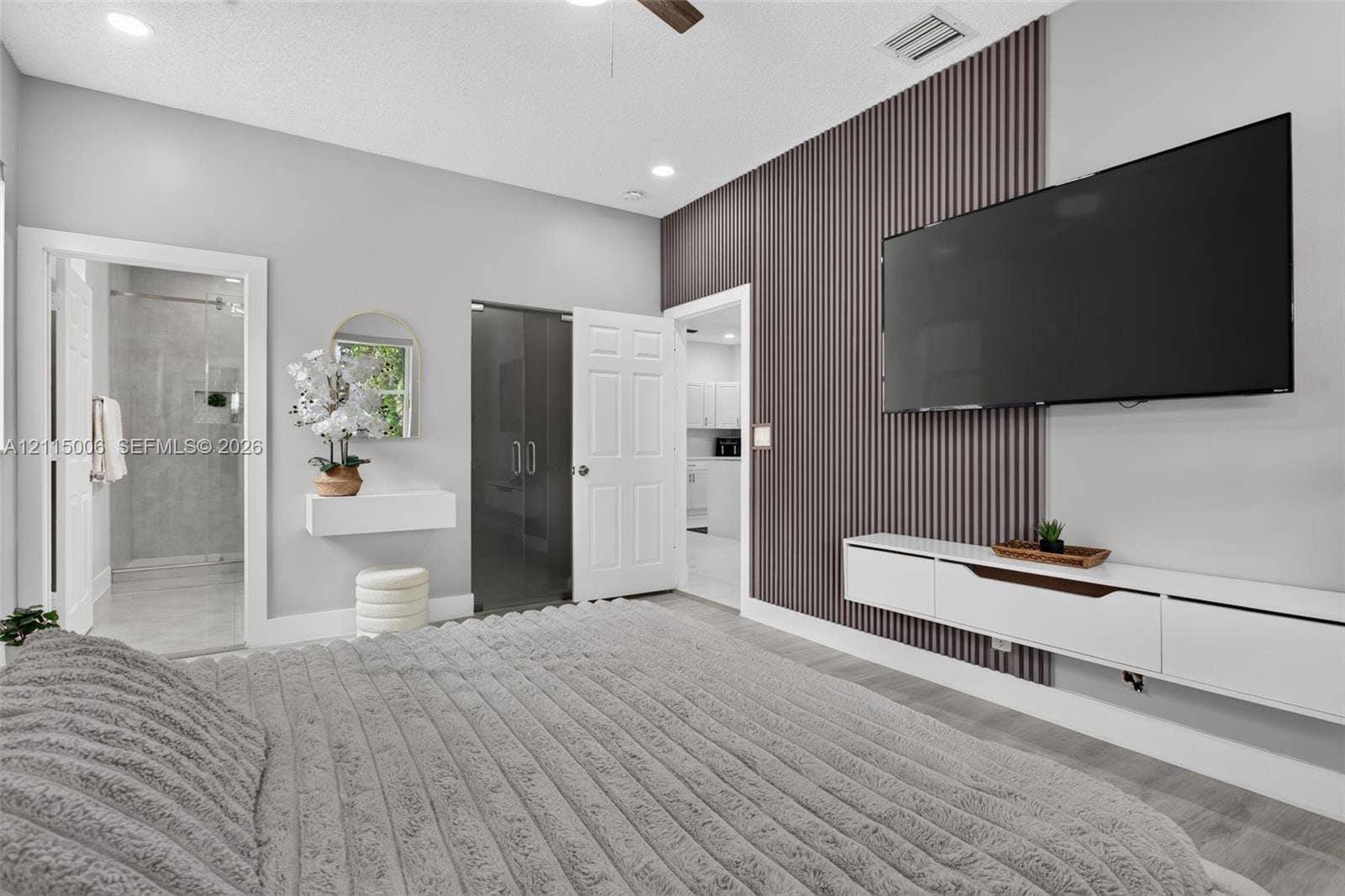 4812 NW 19th Street, Coconut Creek, FL 33063 Vertical slat wood-finish accent wall, wall-mounted white media console, recessed ceiling lighting, ceiling fan, and floating wall shelf