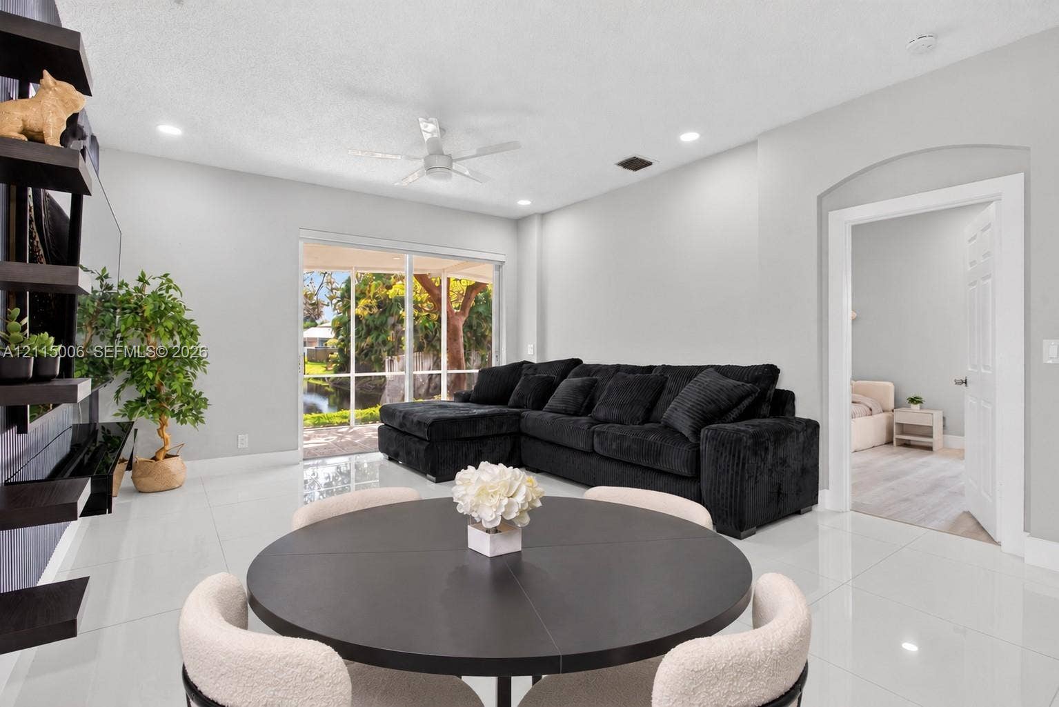 4812 NW 19th Street, Coconut Creek, FL 33063 Living area featuring polished tile flooring, recessed lighting, a ceiling fan, wall-mounted display shelving, and sliding glass doors with a screen-enclosed patio