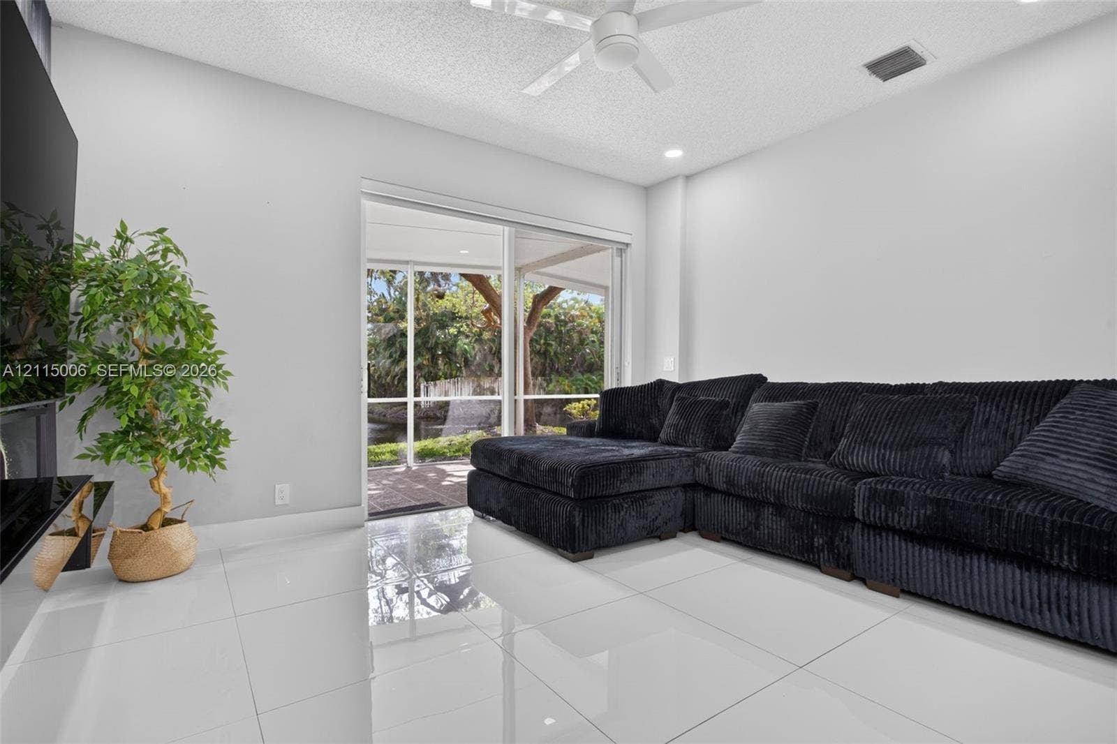 4812 NW 19th Street, Coconut Creek, FL 33063 Large-format tile flooring, ceiling fan, and sliding glass doors opening to a screened lanai with exterior water feature