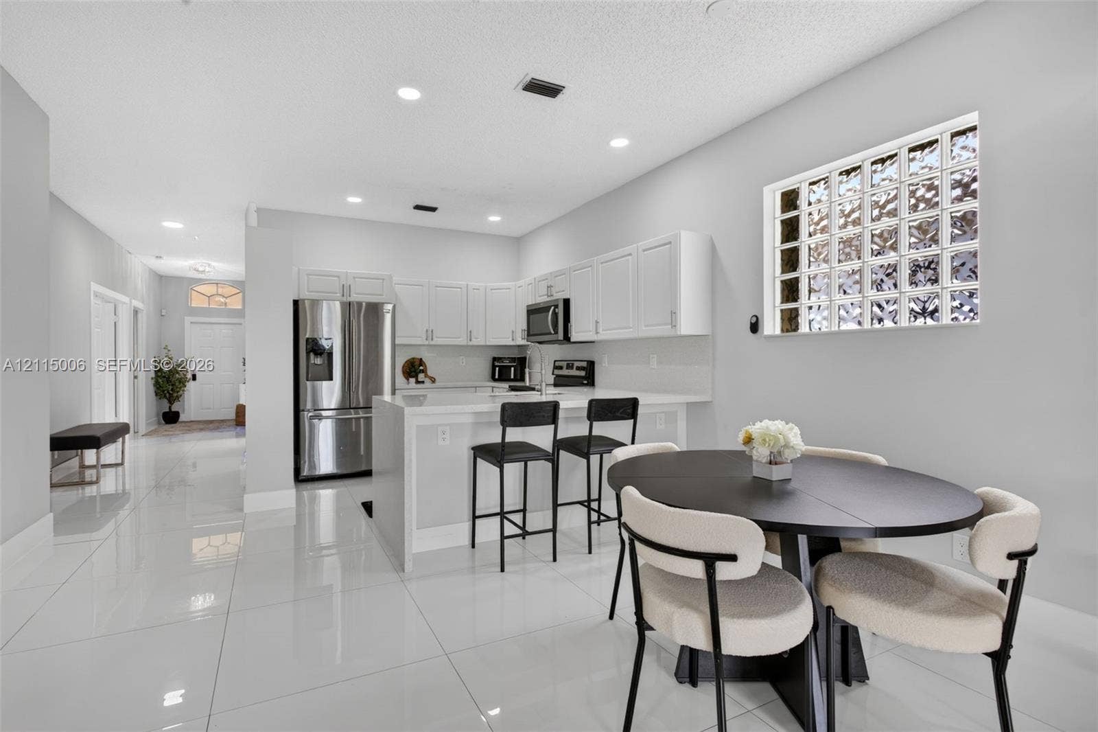4812 NW 19th Street, Coconut Creek, FL 33063 Kitchen featuring white cabinetry, quartz-surface countertops, stainless steel appliances, glass block window, and polished tile flooring