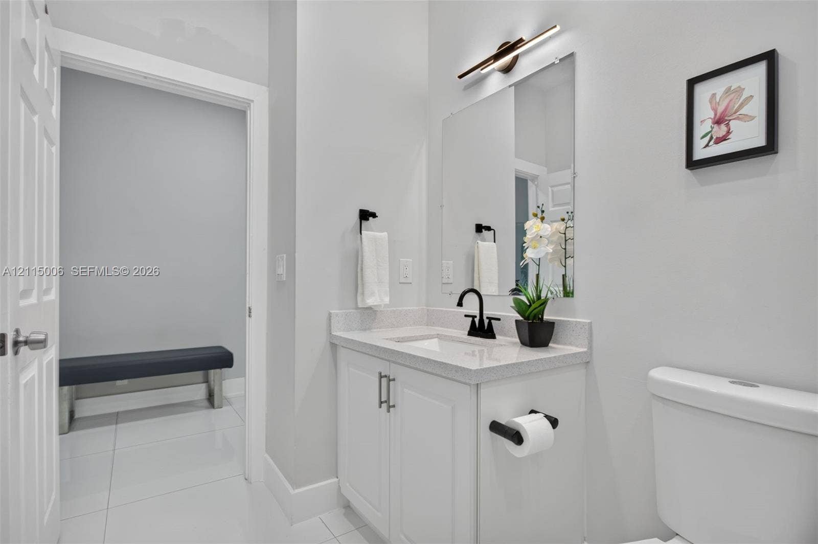 4812 NW 19th Street, Coconut Creek, FL 33063 Bathroom featuring a white vanity with a composite stone countertop, rectangular undermount sink, matte black faucet, and linear LED wall-mounted light fixture