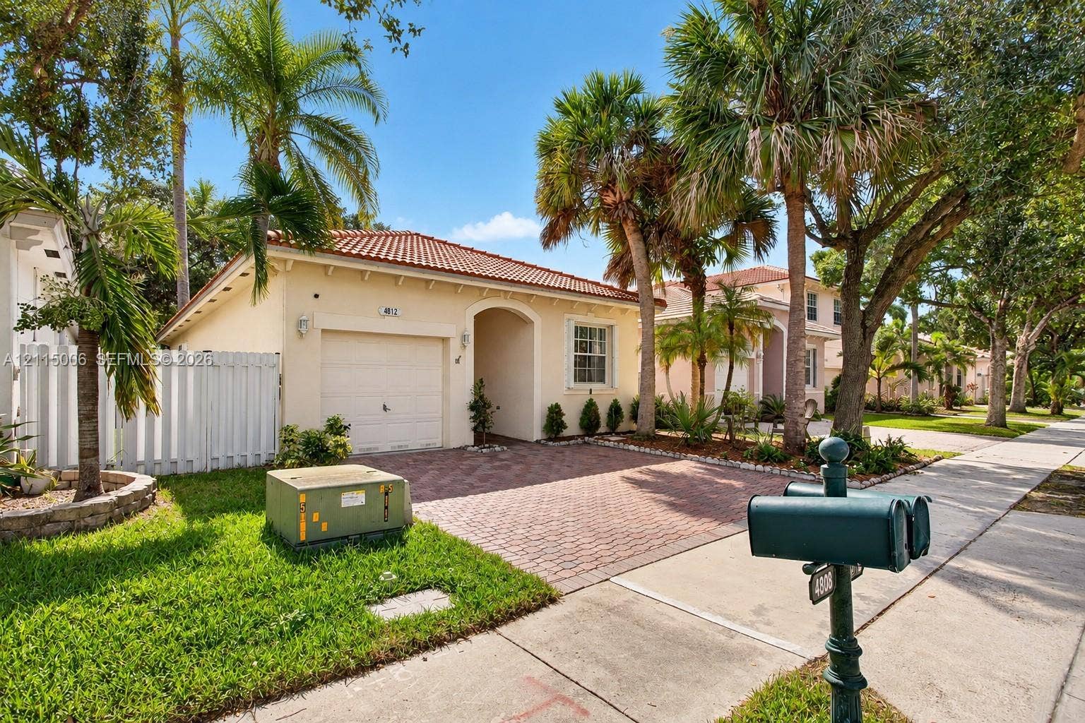 4812 NW 19th Street, Coconut Creek, FL 33063 Single-story residence featuring a barrel-tile roof, paved driveway, attached garage, and white privacy fencing