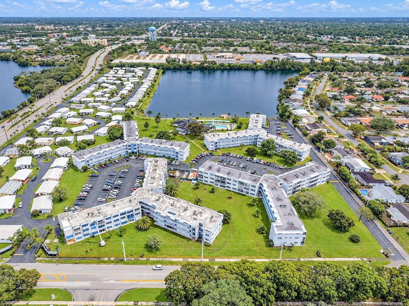 2300 Park Lane, #105, Hollywood, FL 33021 Aerial perspective of a multi-story residential complex featuring waterfront positioning, expansive landscaped grounds, surface parking, and a dedicated swimming pool area