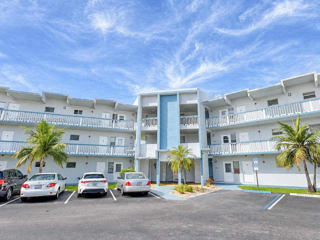 2300 Park Lane, #105, Hollywood, FL 33021 Multi-story exterior featuring light-toned stucco facade, blue accent panels, and covered balconies with white railings