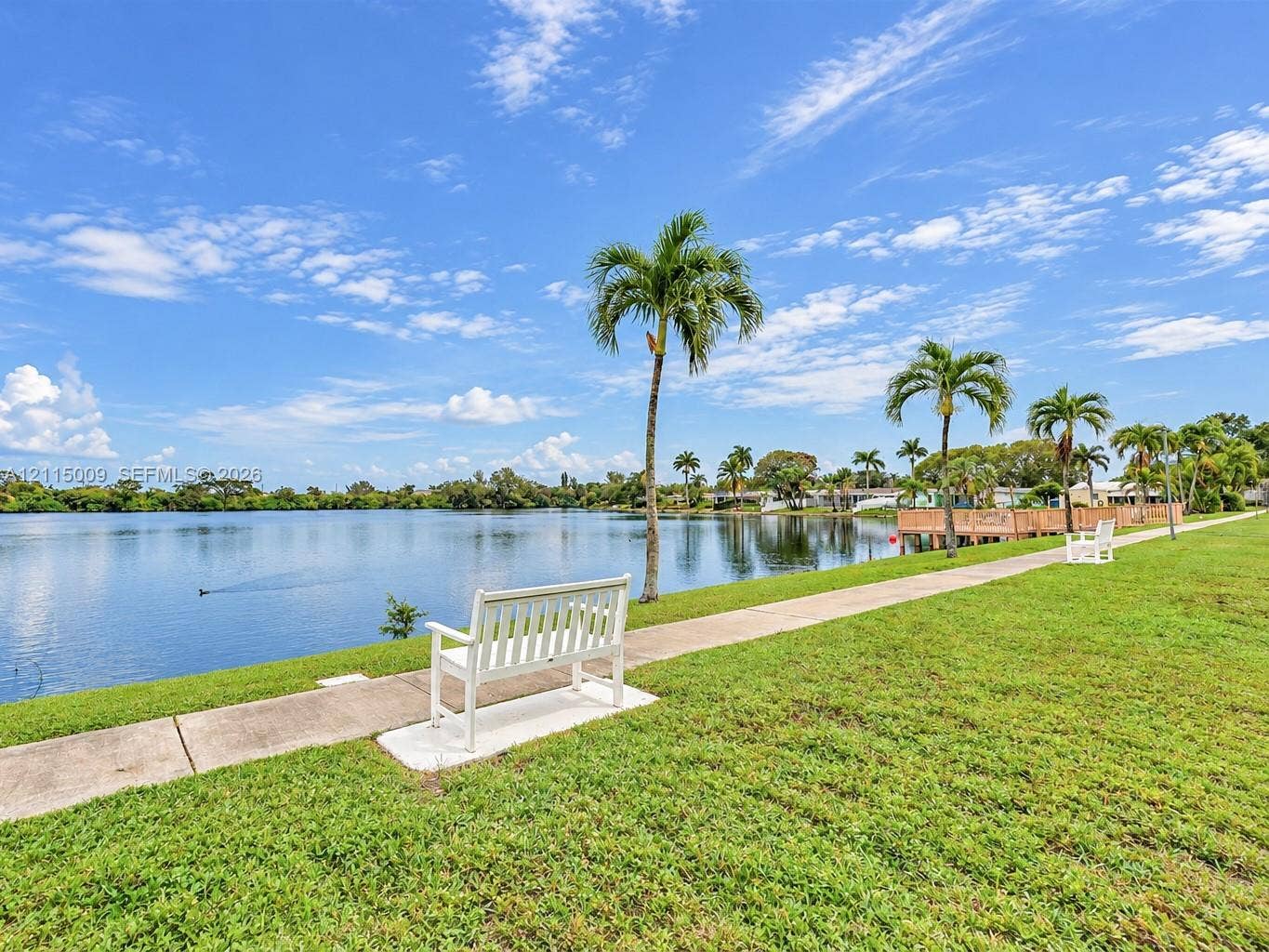 2300 Park Lane, #105, Hollywood, FL 33021 Waterfront property featuring a concrete walking path, manicured lawn, and native palm trees