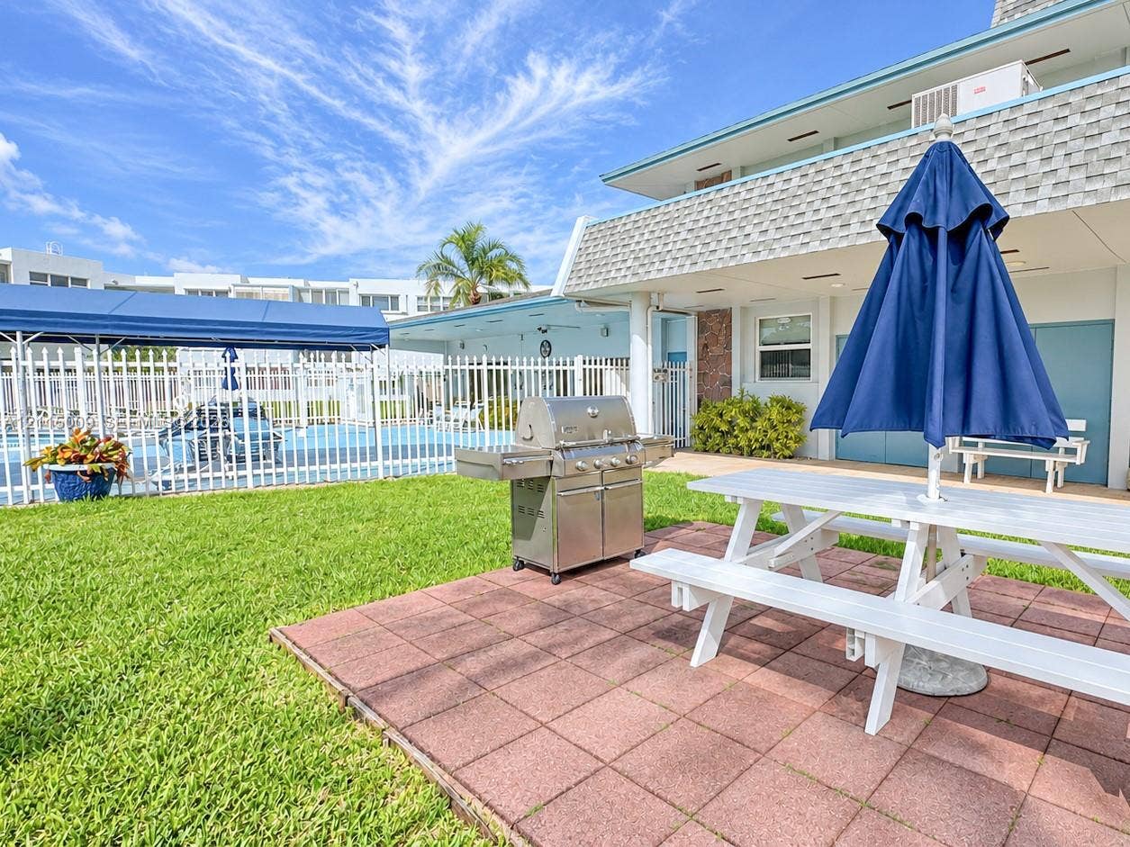 2300 Park Lane, #105, Hollywood, FL 33021 Outdoor space featuring a paved patio, manicured lawn, stainless steel built-in grill, and metal perimeter fencing