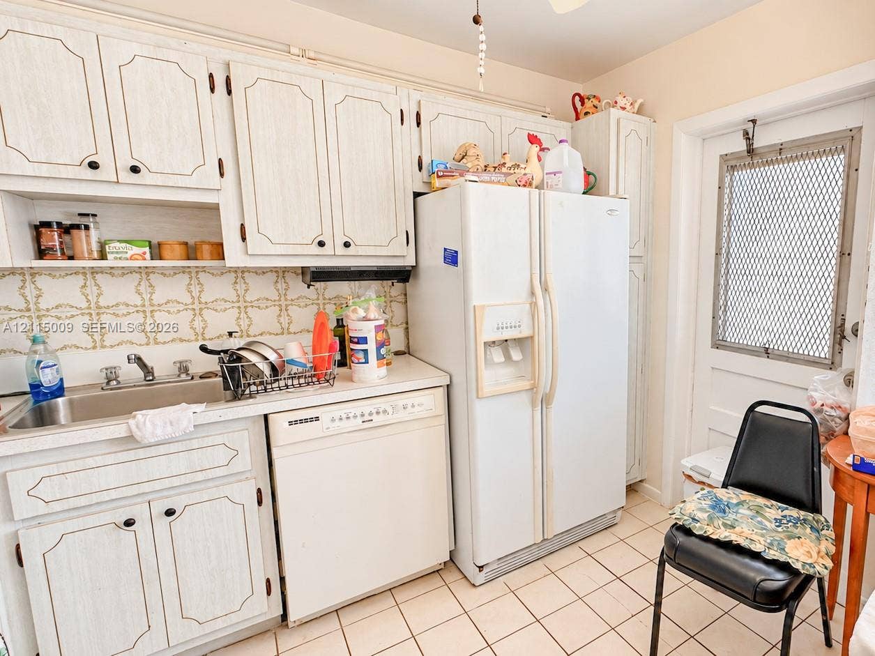 2300 Park Lane, #105, Hollywood, FL 33021 Kitchen featuring white cabinetry, ceramic tile backsplash, integrated stainless steel sink, tile flooring, and a side-by-side refrigerator