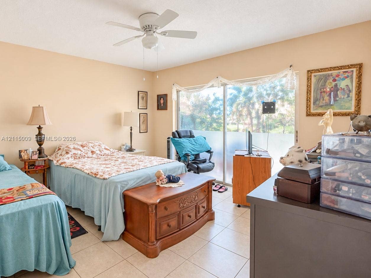 2300 Park Lane, #105, Hollywood, FL 33021 Neutral-toned interior featuring ceramic tile flooring, a white ceiling fan with integrated lighting, and sliding glass doors with privacy tint