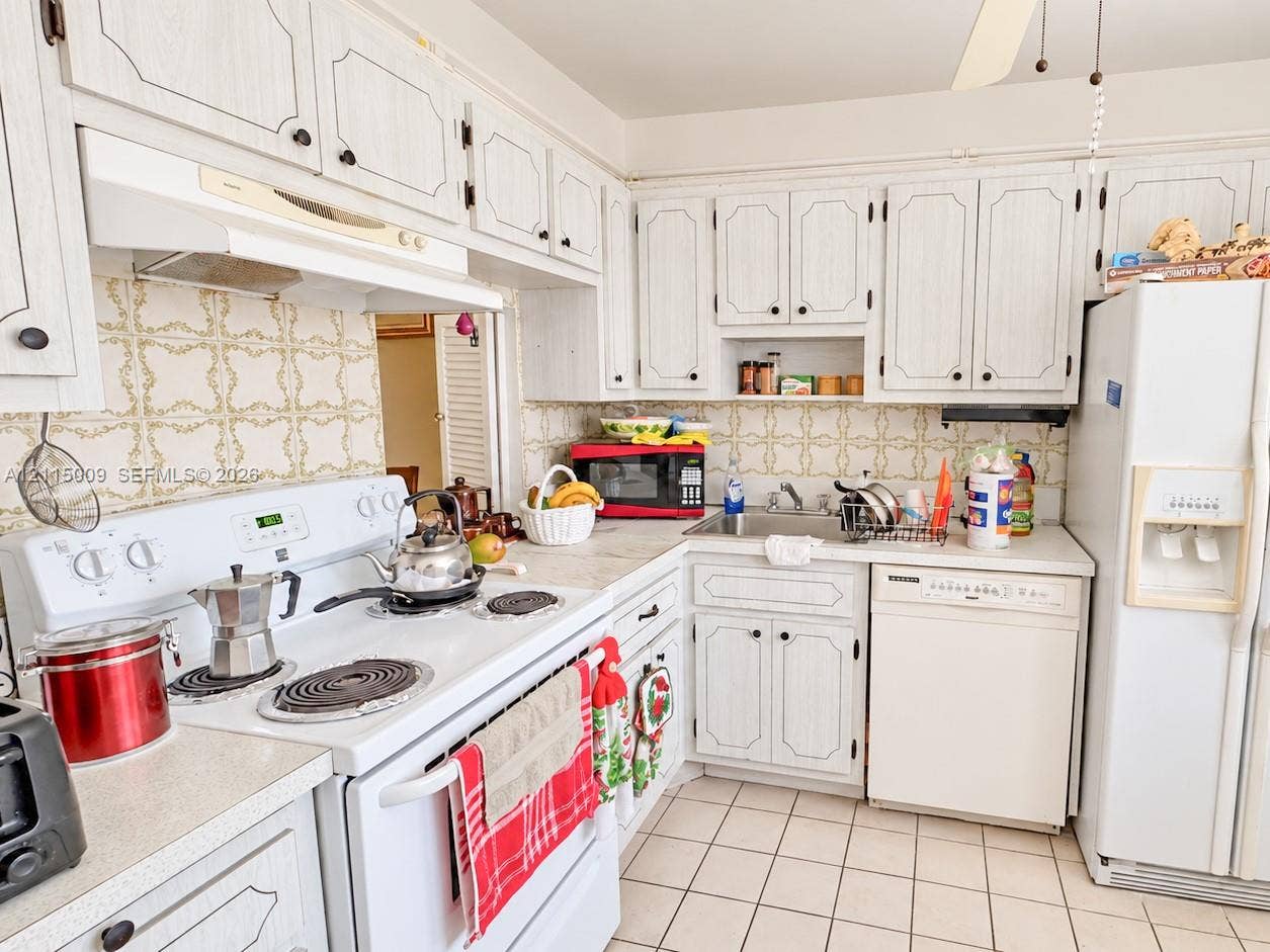 2300 Park Lane, #105, Hollywood, FL 33021 Kitchen featuring white cabinetry with decorative trim, white-finish appliances, light-toned countertops, tile backsplash, and ceramic tile flooring