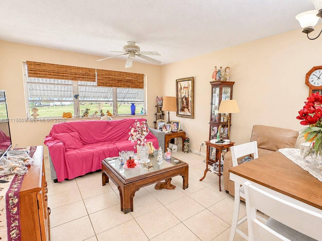 2300 Park Lane, #105, Hollywood, FL 33021 Living area featuring large windows with woven wood shades, light-toned ceramic tile flooring, and a ceiling fan with integrated lighting