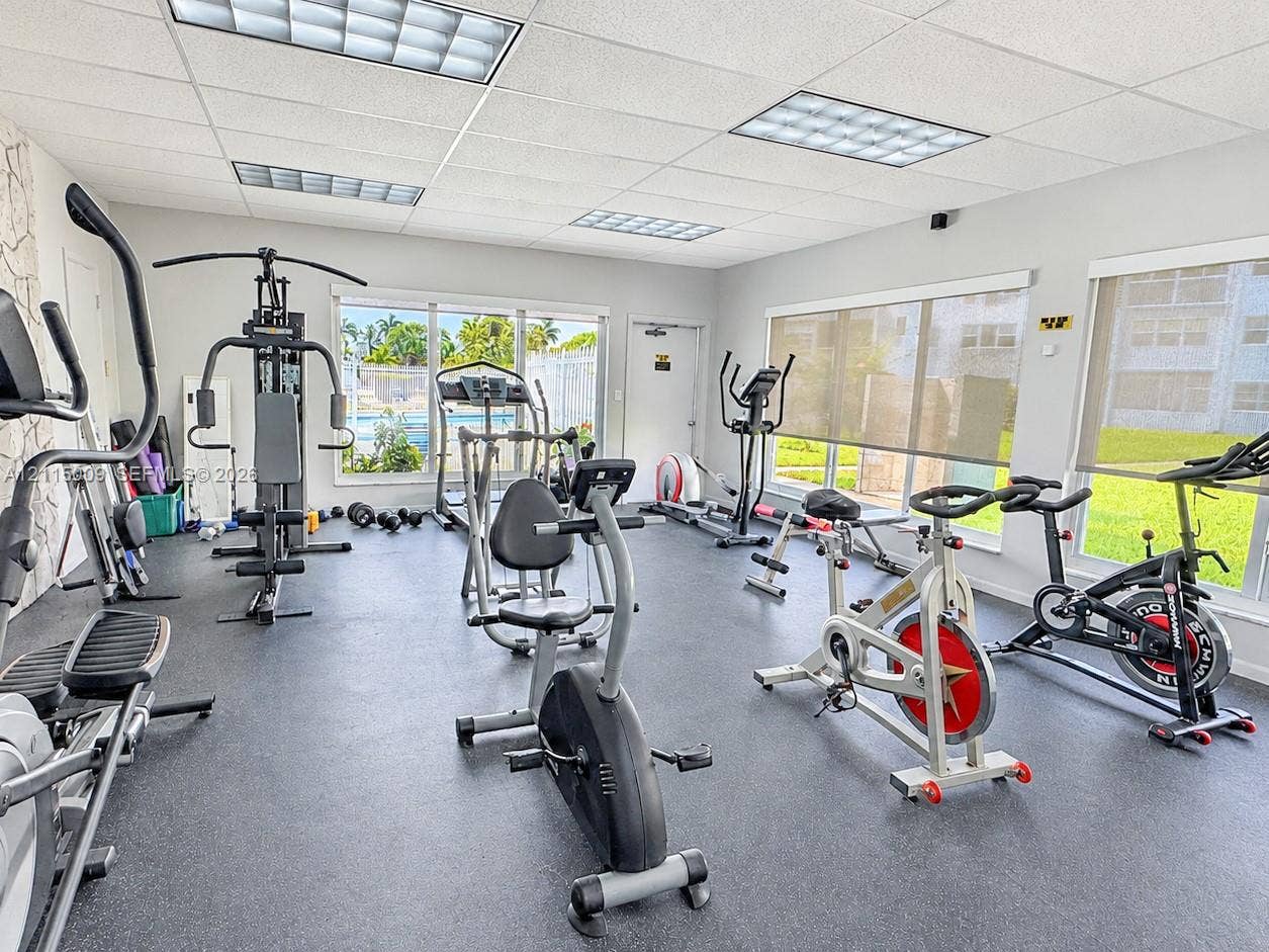 2300 Park Lane, #105, Hollywood, FL 33021 Fitness room featuring rubberized flooring, drop ceiling with recessed panel lighting, and large windows with retractable shades