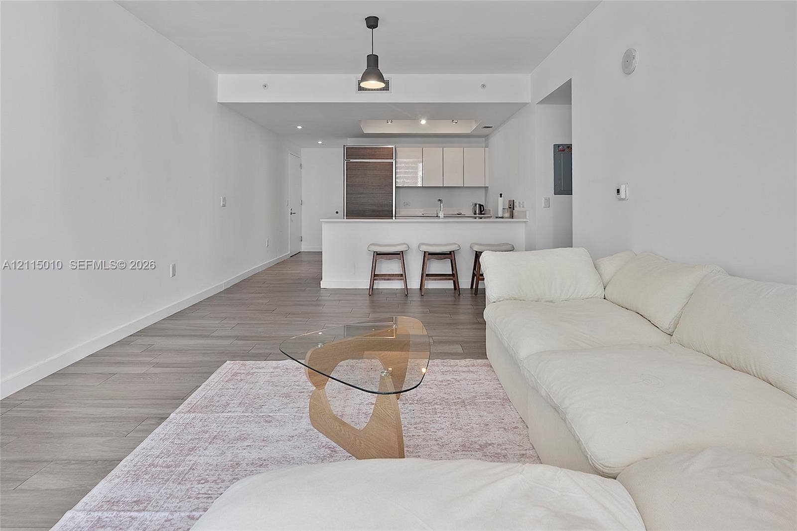 1100 S Miami Avenue, #2407, Miami, FL 33130 Open-concept interior featuring wood-finish flooring, a kitchen island with stone countertops, modern flat-panel cabinetry, and a minimalist pendant light fixture