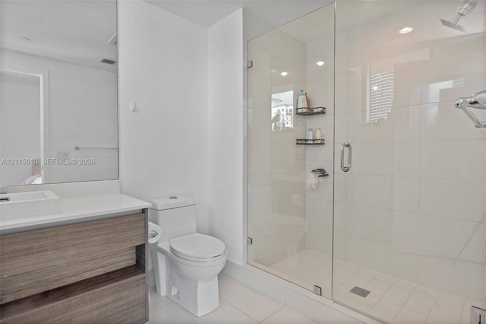 1100 S Miami Avenue, #2407, Miami, FL 33130 Bathroom featuring a wood-finish vanity with an integrated basin, large-format tile flooring, a glass-enclosed walk-in shower with light-toned tile surround, and recessed lighting