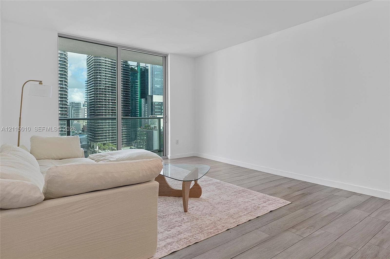 1100 S Miami Avenue, #2407, Miami, FL 33130 Floor-to-ceiling sliding glass doors, urban skyline backdrop, and wood-finish flooring